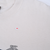 Close-up of white tee fabric showing a small reddish spot near the chest graphic