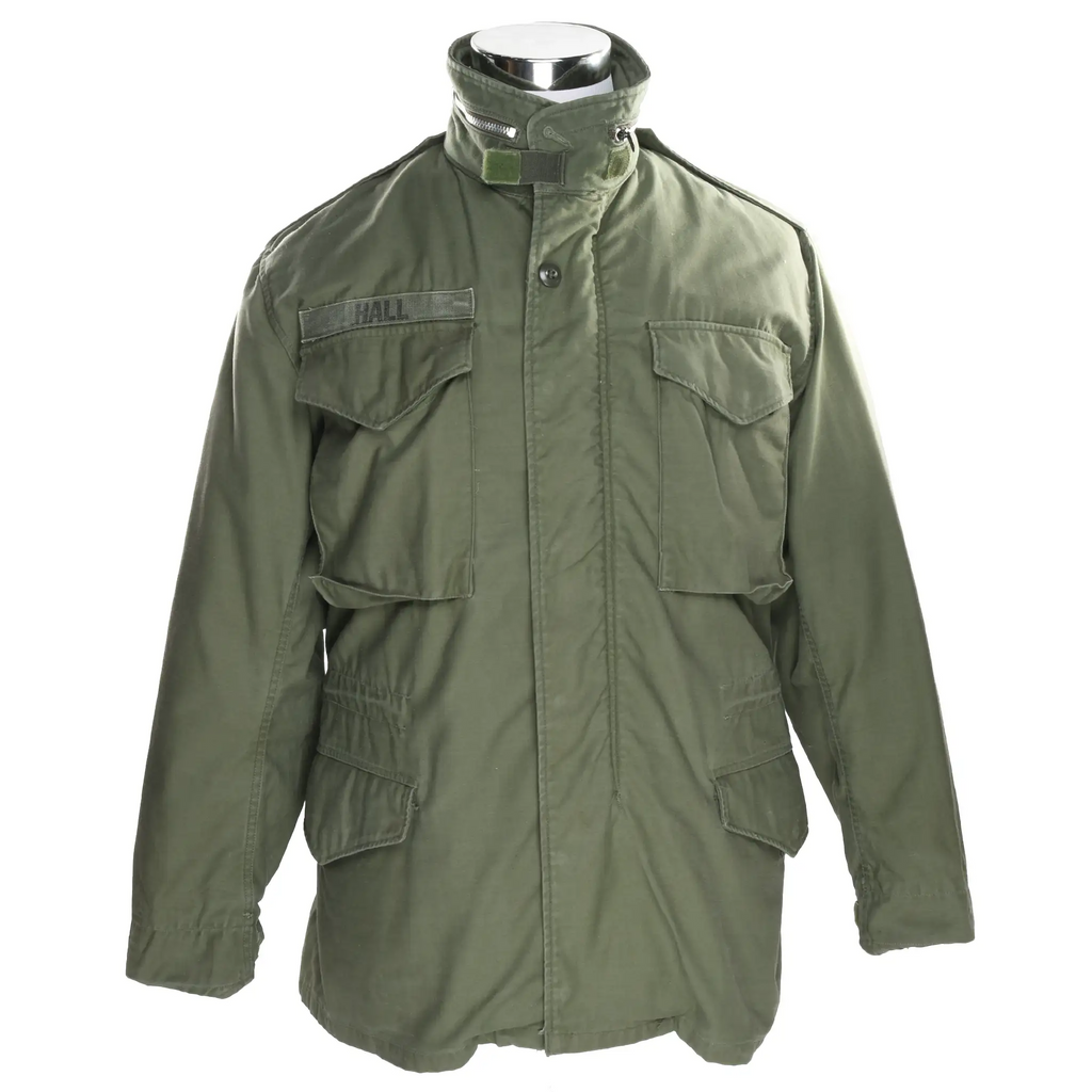 Front of olive green US Army M65 field jacket with four flap pockets and Hall name tape