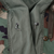 Close-up of the M65 jacket's interior waist drawcords, zipper and button