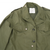 Upper front detail of field jacket with collar, chest flap pockets, buttons and inside label