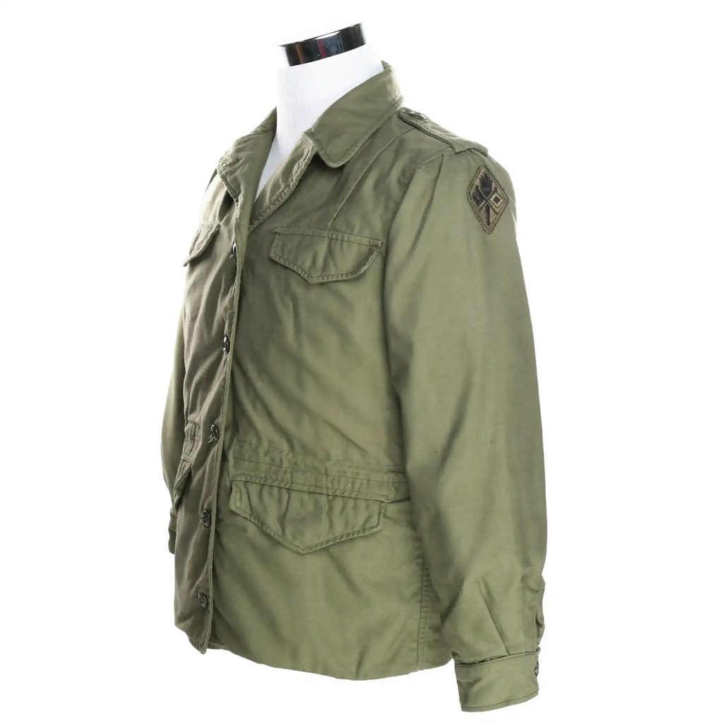 Three-quarter front view of olive green US Army woman's field jacket with shoulder patch and flap pockets