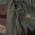 Interior detail of US Army M65 jacket showing olive waist drawcords, zipper, snap and woodland camo shell.