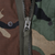 Close-up of the front zipper and snap fasteners on the US Army M65 woodland camo field jacket.